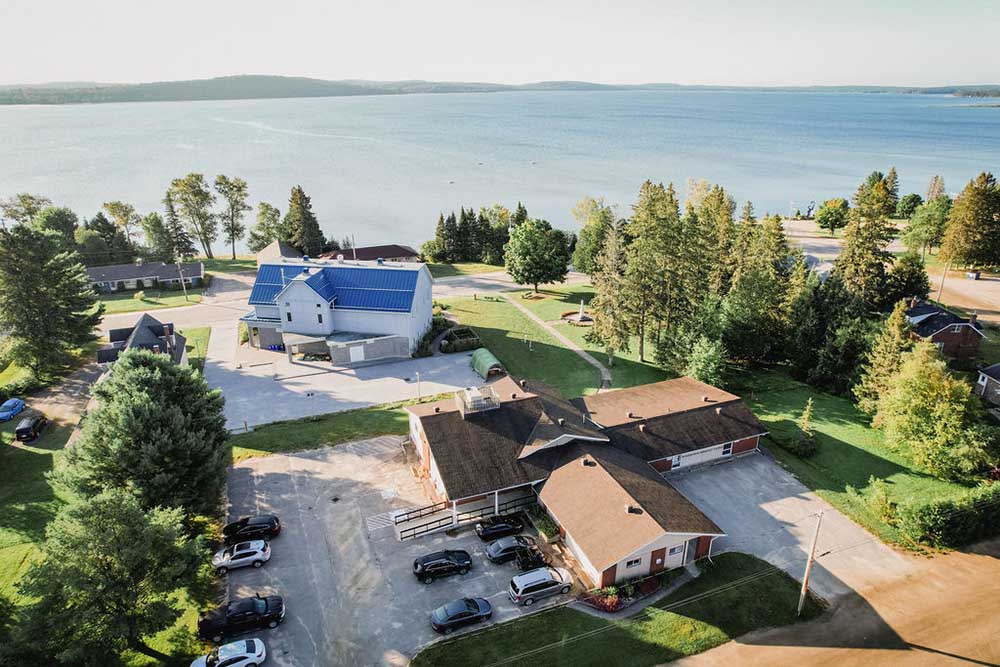 Aerial view of the AHFHT Sundridge office, showing the parking lot, exterior of the building, and a lake in the background.